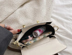 Beige handbag with floral patterned lining, containing a can of whipped cream and other items, held by a person.