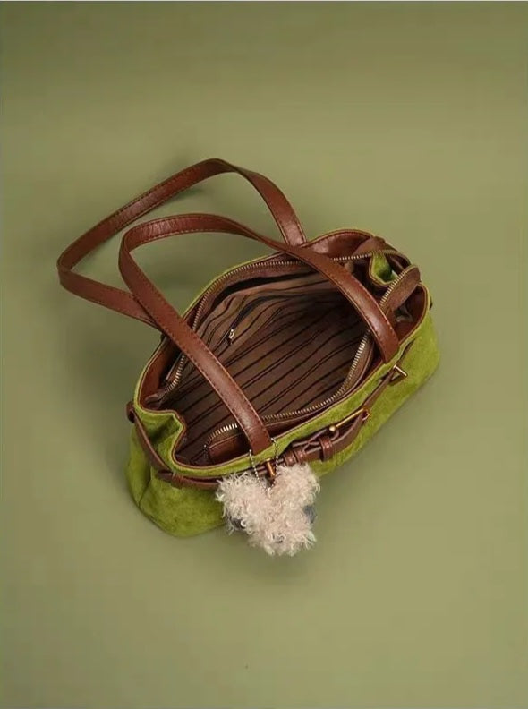 Green handbag with brown leather accents on a green background