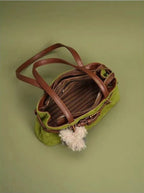 Green handbag with brown leather accents on a green background