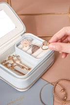 Jewelry set including rings and necklaces in a white jewelry box with a hand holding a ring.
