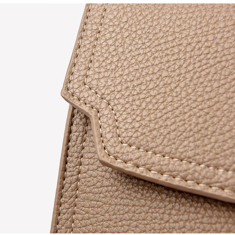 Close-up of beige leather bag corner with visible stitching on a white background