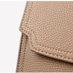 Close-up of beige leather bag corner with visible stitching on a white background
