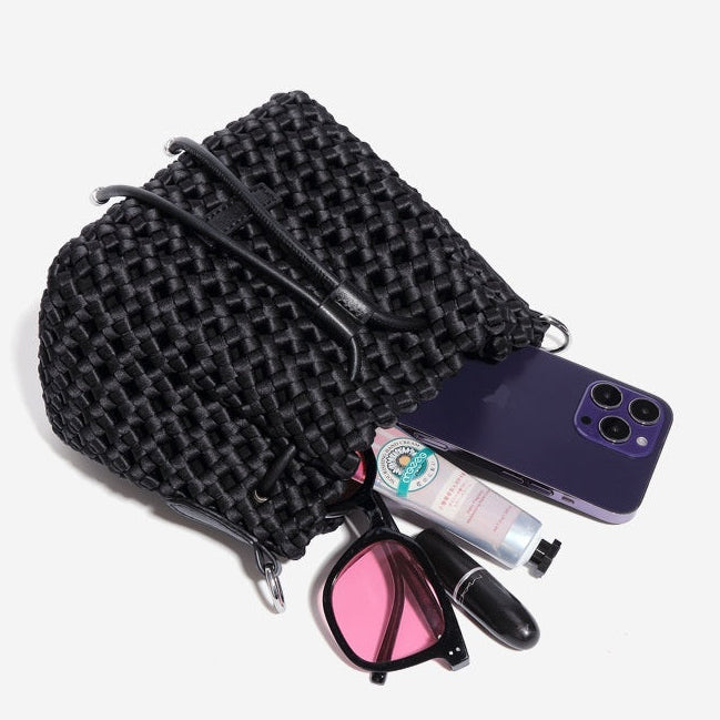 Black woven pouch with phone, lipstick, wallet, glasses, and sunscreen on a white background