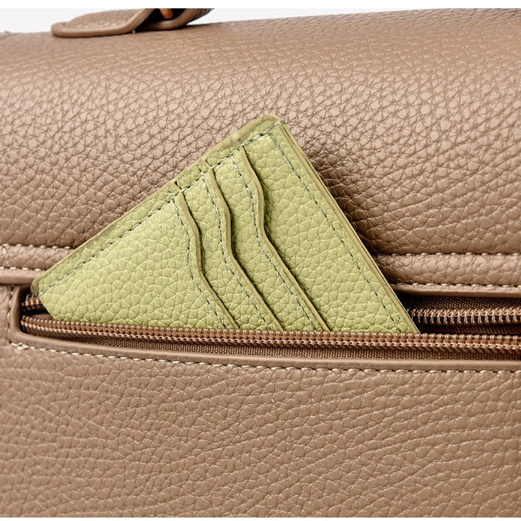 Close-up of a beige leather handbag with a green patch on a matching background.