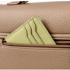 Close-up of a beige leather handbag with a green patch on a matching background.