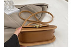 Brown handbag with a wear-resistant bottom feature on a neutral background